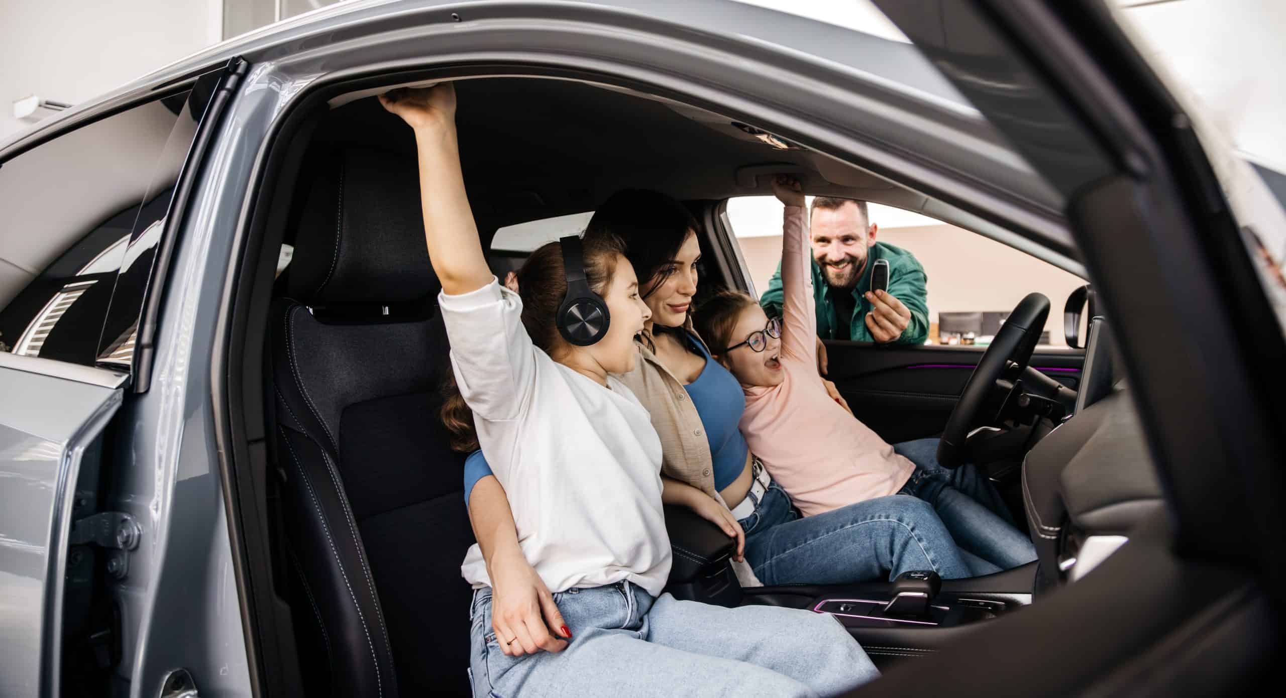 A happy young family gets the keys to their new car at a modern car dealership. The end of a test drive or purchase of a new car.